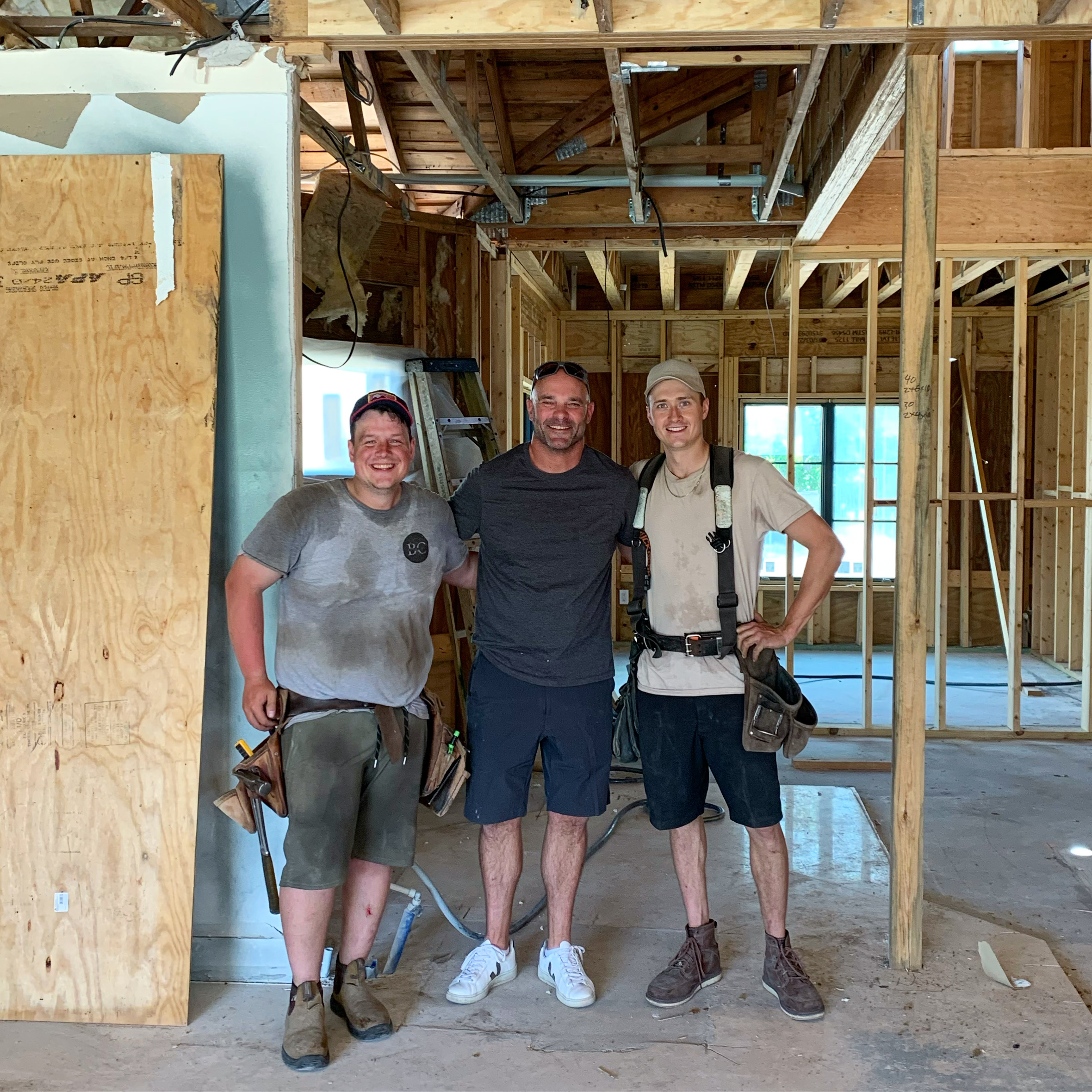 Three men standing in construction site.